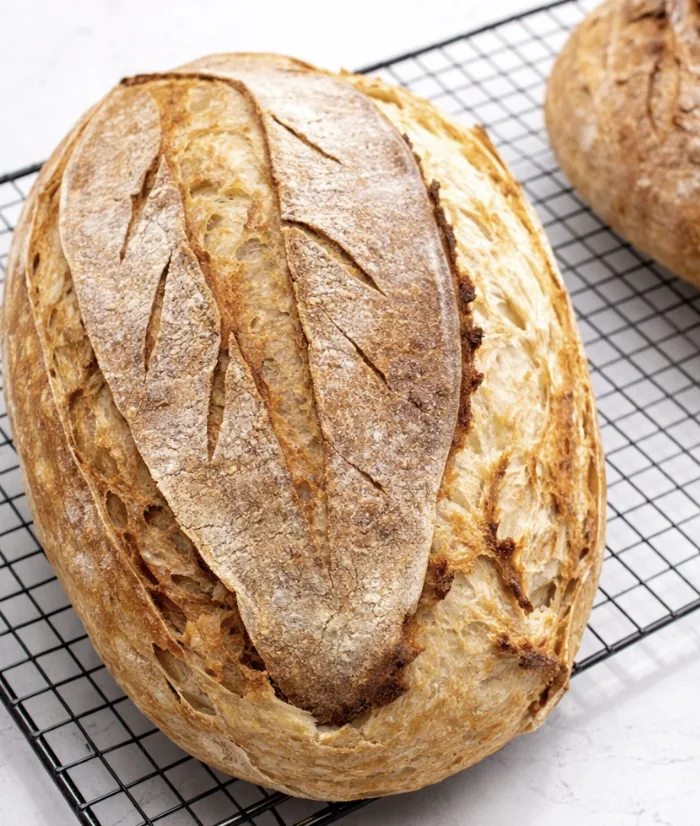 Hand-scored rustic sourdough loaf cooling on a wire rack
